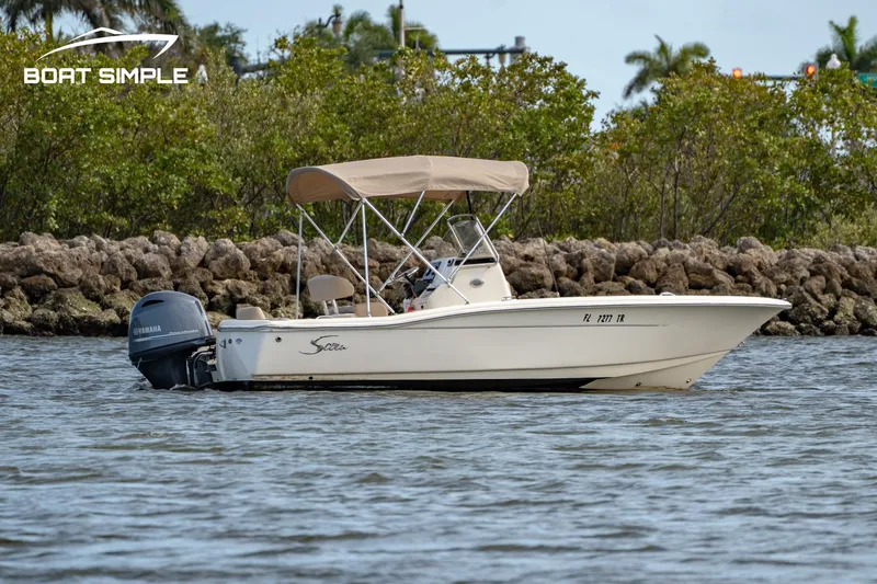 Slide: The Image of 2021 Scout 195 Sportfish boat on water, with outboard motor and canopy. - 0