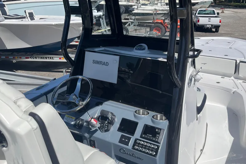 Slide: The Image of 2025 Tidewater 2700 Carolina Bay boat dashboard with Simrad electronics and steering wheel. - 11