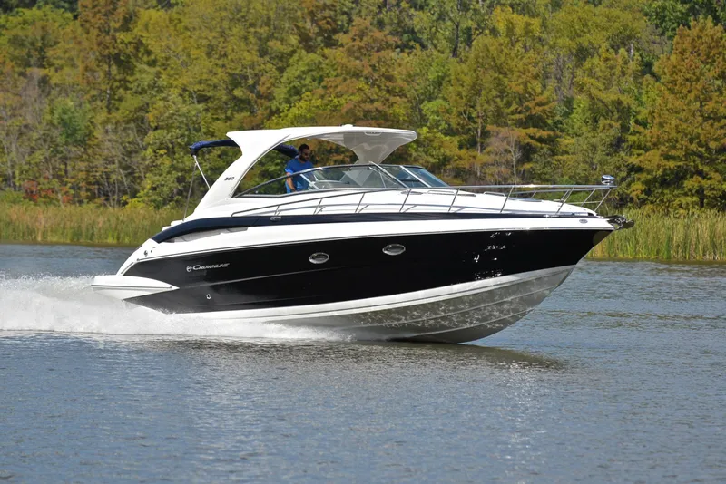 Slide: The Image of 2020 Crownline 350 SY cruising on a lake with lush green trees in the background. - 1