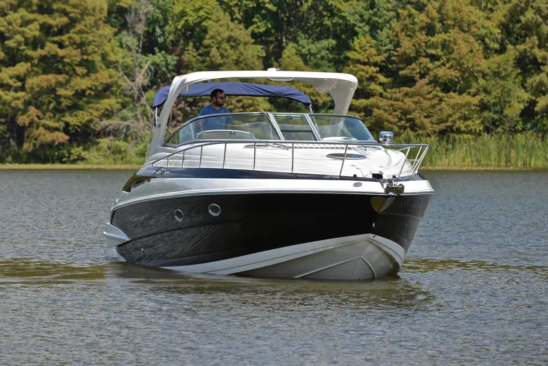 Slide: The Image of 2020 Crownline 350 SY boat cruising on a lake with lush green trees in the background. - 14