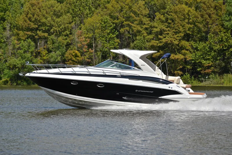 Slide: The Image of 2020 Crownline 350 SY cruising on a lake with forested background. - 2