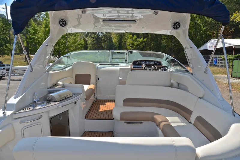 Slide: The Image of 2020 Crownline 350 SY boat interior with white and beige seating, outdoor kitchen, and helm. - 23