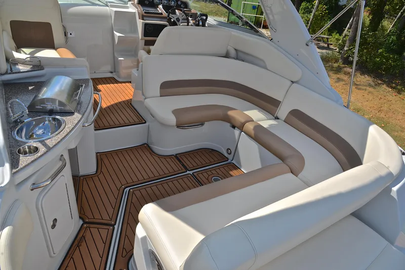 Slide: The Image of 2020 Crownline 350 SY boat interior with white and brown seating, wood flooring, and kitchenette. - 24