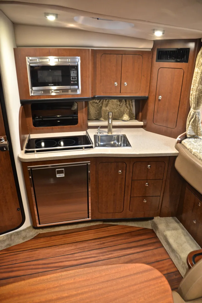Slide: The Image of 2020 Crownline 350 SY yacht kitchen with microwave, sink, and wooden cabinetry. - 42