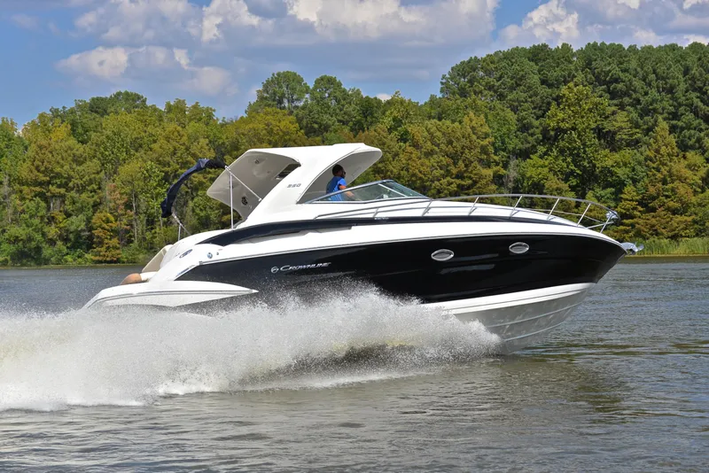 Slide: The Image of 2020 Crownline 350 SY boat cruising on a lake with lush green trees in the background. - 5