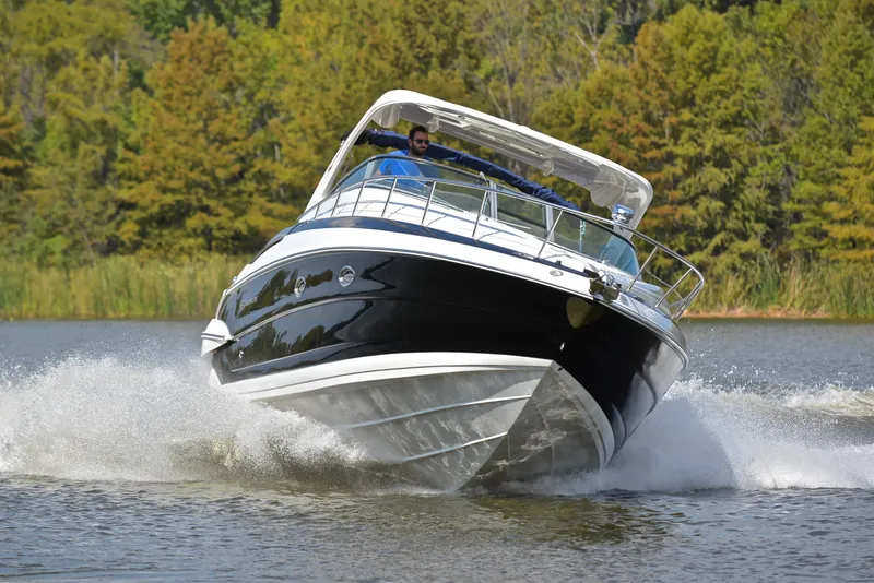 Slide: The Image of 2020 Crownline 350 SY cruising on a lake with lush green trees in the background. - 7