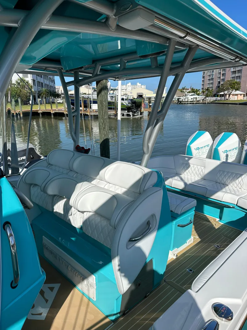 Slide: The Image of 2020 Nor-Tech 390 Sport boat with white seating and turquoise accents docked by waterfront homes. - 40