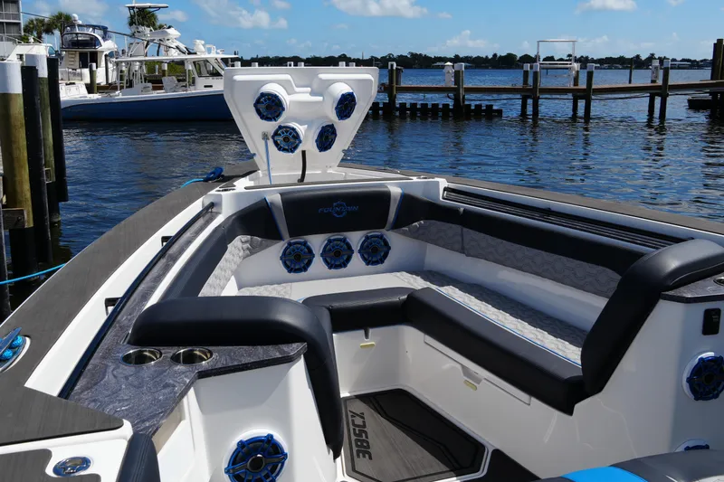 Slide: The Image of 2024 Fountain 38 SCX boat interior with luxurious seating and speakers, docked by the water. - 31