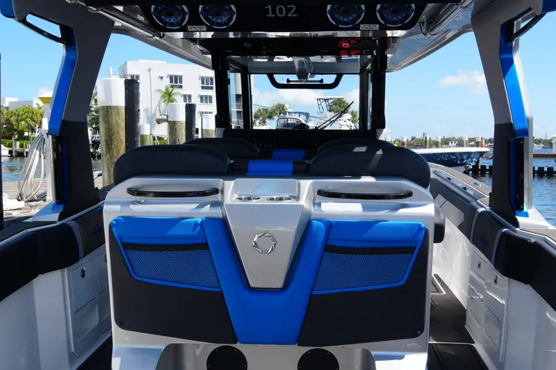 Slide: The Image of 2024 Fountain 38 SCX boat interior with blue and black seating, docked by waterfront. - 44