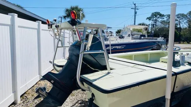 Slide: The Image of 1983 Maverick 18 Flats Boat with outboard motor, parked near a white fence. - 6