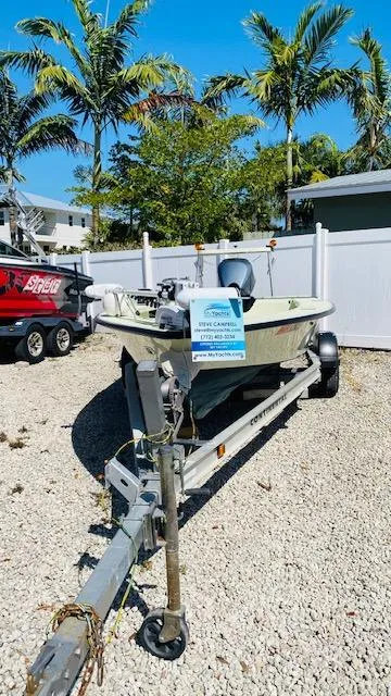 Slide: The Image of 1983 Maverick 18 Flats Boat on trailer, parked outdoors with palm trees in the background. - 2
