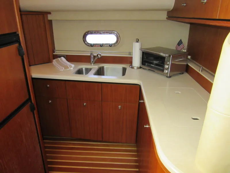 Slide: The Image of 2006 Tiara Yachts 4300 Sovran galley with wood cabinetry and stainless steel sink. - 14