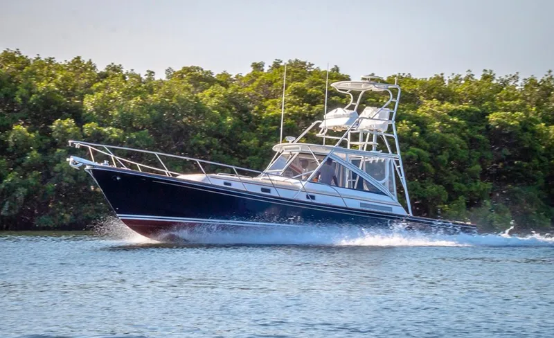 Slide: The Image of 2000 Little Harbor 42 Whisper Jet cruising on water near lush greenery. - 1