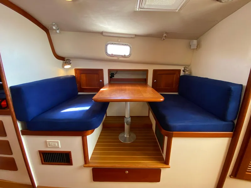 Slide: The Image of Interior dining area of 2000 Little Harbor 42 Whisper Jet with blue cushions and wooden table. - 32