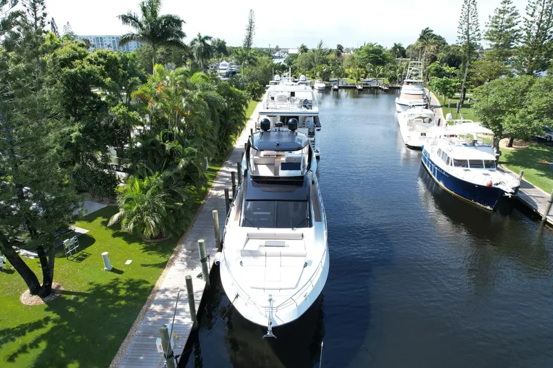 Slide: The Image of 2024 Astondoa Flybridge yacht docked in a scenic marina with lush greenery. - 4