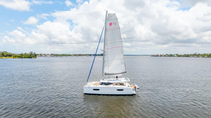 Slide: The Image of 2018 Fountaine Pajot Lucia 40 catamaran sailing on a calm, scenic waterway. - 24