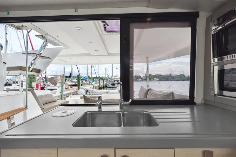 Slide: The Image of Interior view of 2018 Fountaine Pajot Lucia 40 catamaran kitchen with marina backdrop. - 32