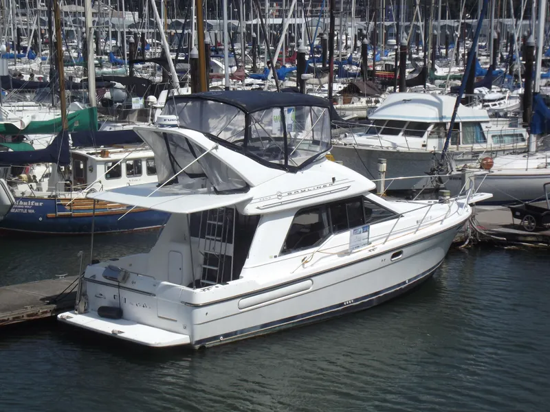 The Image of 2000 Bayliner 3388 Motor Yacht docked in a marina, surrounded by other boats. - 0