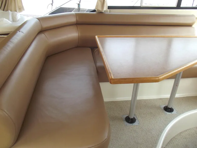 Slide: The Image of Interior of 2000 Bayliner 3388 Motor Yacht with tan leather seating and wooden table. - 12