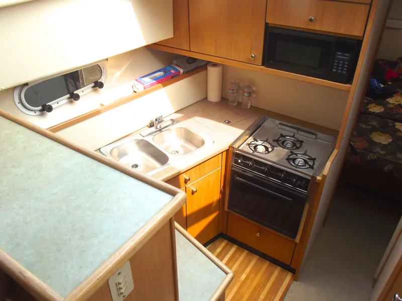 Slide: The Image of 2000 Bayliner 3388 Motor Yacht kitchen with stove, sink, and microwave. - 18