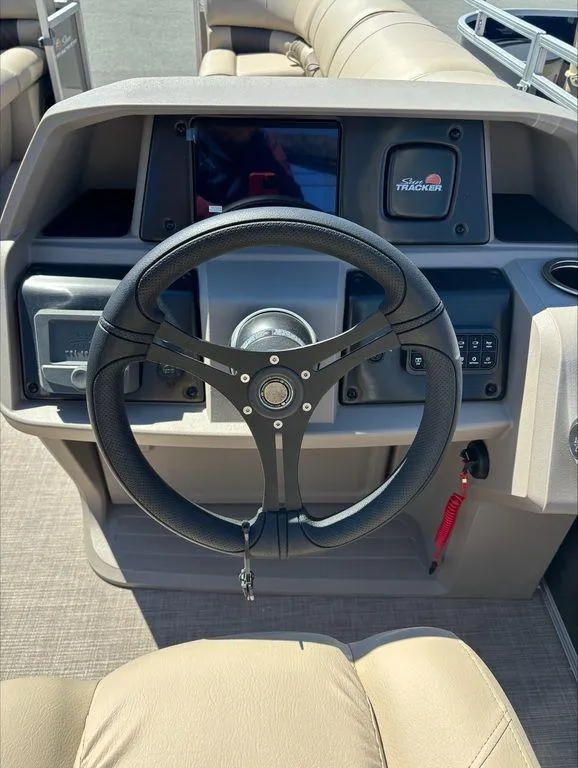 Slide: The Image of 2022 Sun Tracker PB 24 DLX boat steering console with modern controls and beige seating. - 9