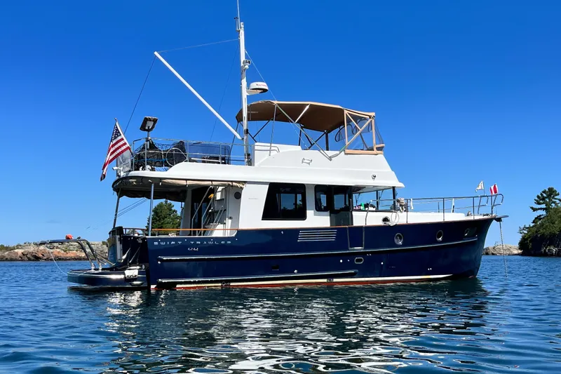 Slide: The Image of 2017 Beneteau Swift Trawler 44 on calm water with clear blue sky. - 0