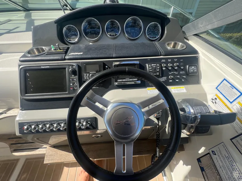 Slide: The Image of 2014 Sea Ray 350 Sundancer helm with steering wheel, gauges, and navigation controls. - 12