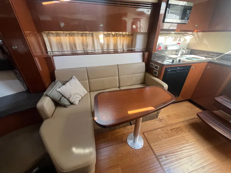Slide: The Image of 2014 Sea Ray 350 Sundancer interior with beige leather seating and wooden table. - 30