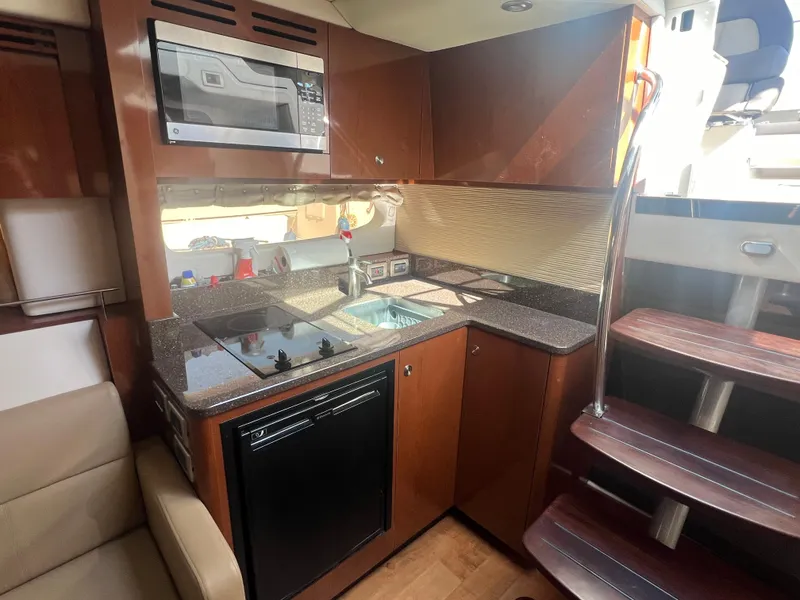 Slide: The Image of 2014 Sea Ray 350 Sundancer kitchen with microwave, stove, and wooden cabinetry. - 34