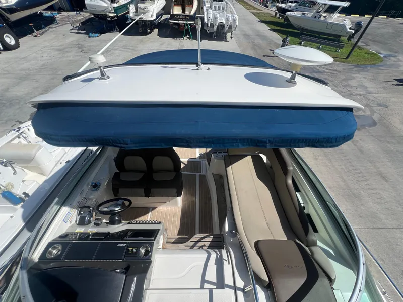 Slide: The Image of 2014 Sea Ray 350 Sundancer boat interior with helm, seating, and blue canopy. - 8