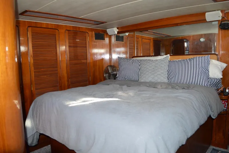Slide: The Image of 1986 Gulfstar 49 Motor Yacht master bedroom with wooden cabinetry and cozy bedding. - 16