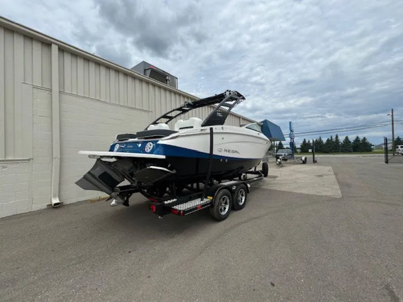 Slide: The Image of 2024 Regal LS4 Surf boat on trailer, parked outdoors under cloudy sky. - 3