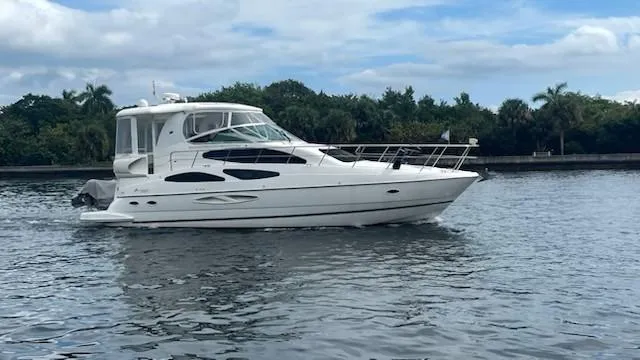 Slide: The Image of 2004 Cruisers Yachts 455 Express Motoryacht on calm water, surrounded by lush greenery. - 25