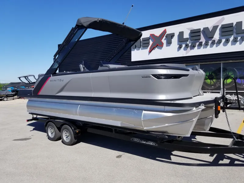 The Image of 2024 Manitou Explorer 22 Max Bench pontoon boat on trailer at dealership. - 0