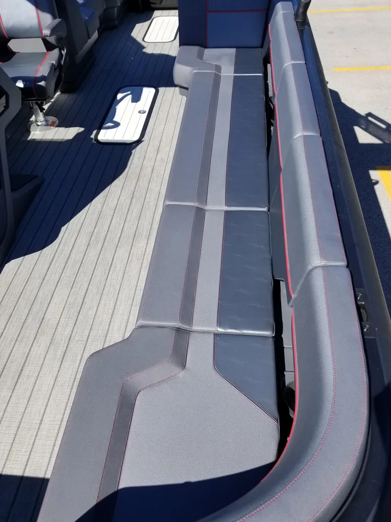 Slide: The Image of 2024 Manitou Explorer 22 Max Bench seating area with gray upholstery and red accents. - 10