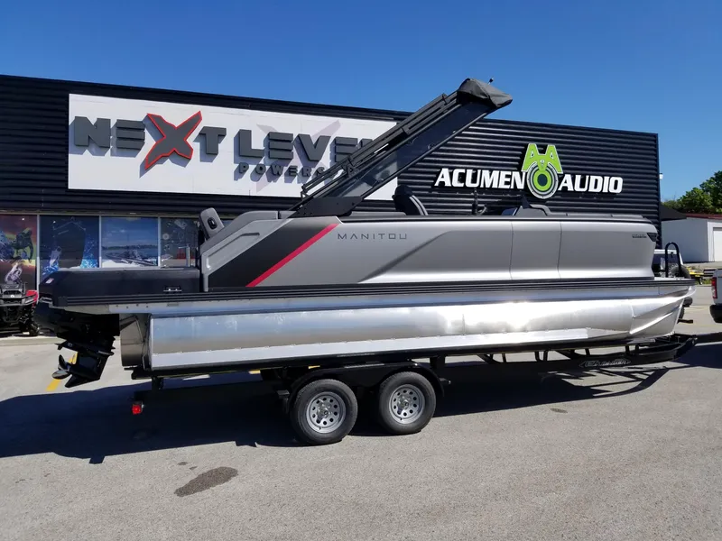 Slide: The Image of 2024 Manitou Explorer 22 Max Bench pontoon boat on trailer outside Next Level Powersports. - 17