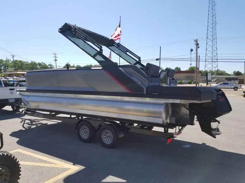 Slide: The Image of 2024 Manitou Explorer 22 Max Bench pontoon boat on trailer in parking lot. - 2