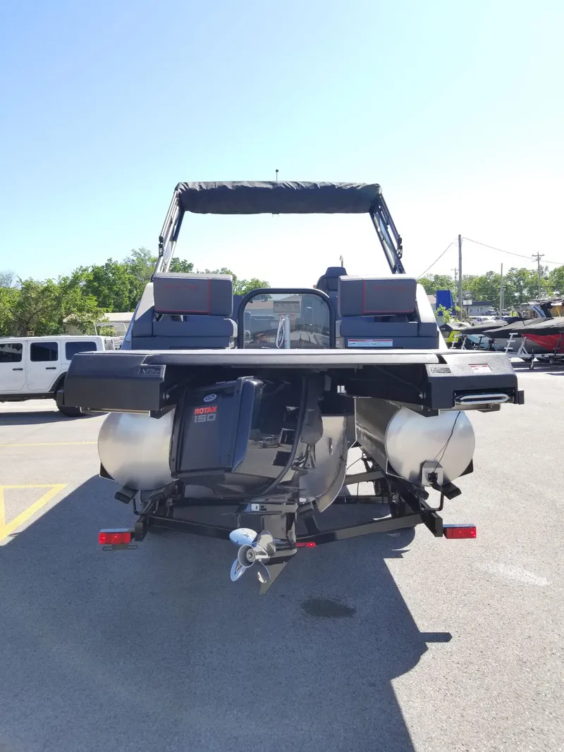 Slide: The Image of 2024 Manitou Explorer 22 Max Bench pontoon boat, rear view in a parking lot. - 3