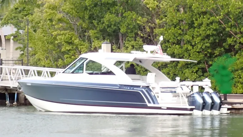 Slide: The Image of 2021 Formula 380 Super Sport Crossover OB boat docked near lush greenery. - 1