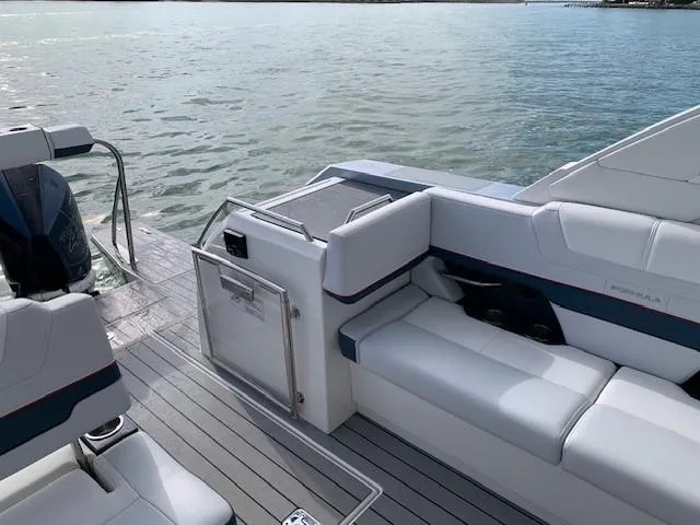 Slide: The Image of 2021 Formula 380 Super Sport Crossover OB boat interior with white seating and lake view. - 13