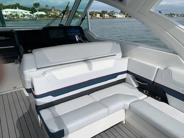 Slide: The Image of 2021 Formula 380 Super Sport Crossover OB interior with white and blue seating, docked by waterfront homes. - 4