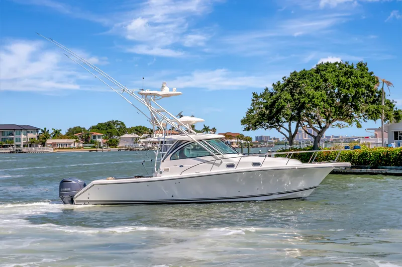 Slide: The Image of 2016 Pursuit 385OS boat cruising on a sunny day near waterfront homes. - 12