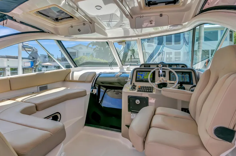 Slide: The Image of 2016 Pursuit 385OS boat interior with beige leather seating and modern dashboard. - 14