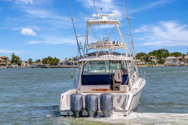 Slide: The Image of 2016 Pursuit 385OS boat with triple outboard engines cruising on water. - 2