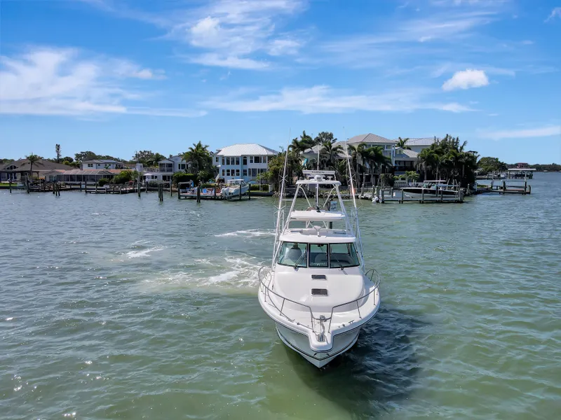 Slide: The Image of 2016 Pursuit 385OS boat cruising near waterfront homes on a sunny day. - 6