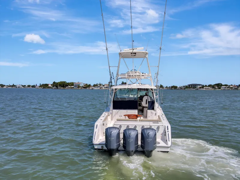 Slide: The Image of 2016 Pursuit 385OS boat with triple outboard engines on open water. - 9