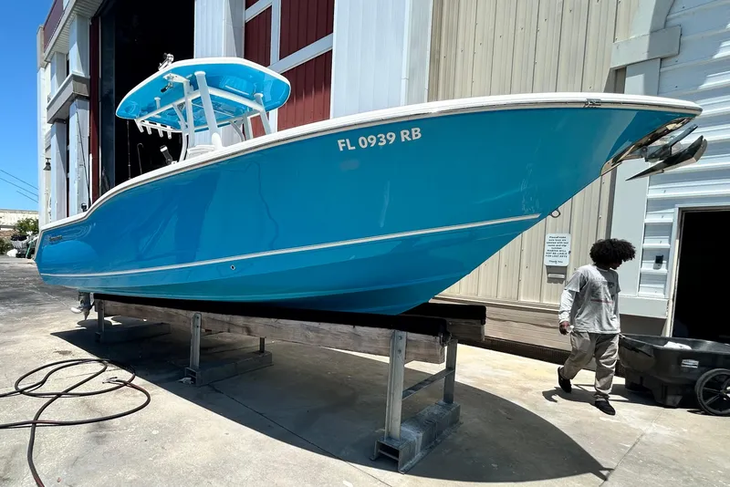 Slide: The Image of 2016 Tidewater 252 CC Adventure boat in blue, docked outside a warehouse. - 5