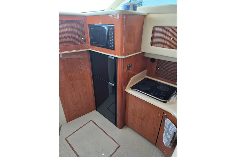 Slide: The Image of Interior of 2000 Sea Ray 400 Sedan Bridge with kitchen appliances and wood cabinetry. - 12