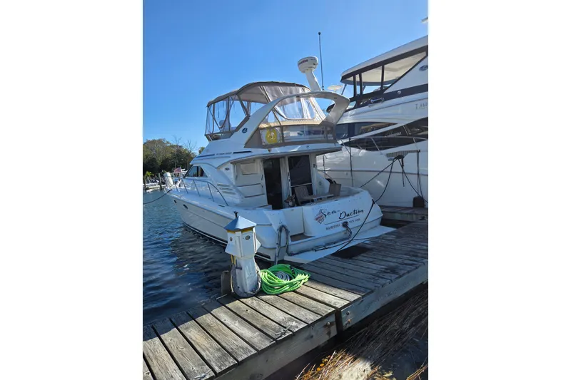 Slide: The Image of 2000 Sea Ray 400 Sedan Bridge docked at marina, clear sky, green hose on pier. - 2