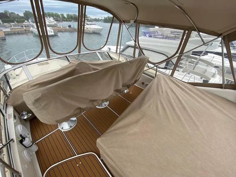 Slide: The Image of 2000 Sea Ray 400 Sedan Bridge yacht interior with covered seating and wooden deck. - 9